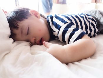 Close-up of baby sleeping on bed at home