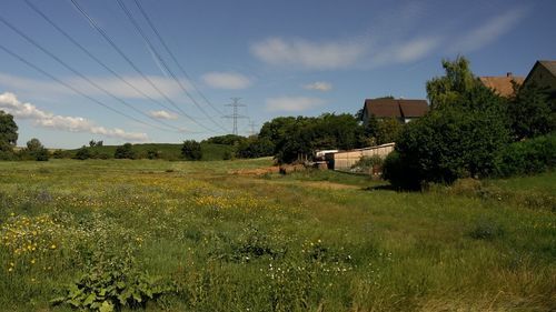 Electricity pylon on field against cloudy sky