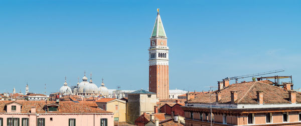 Buildings in city against clear blue sky