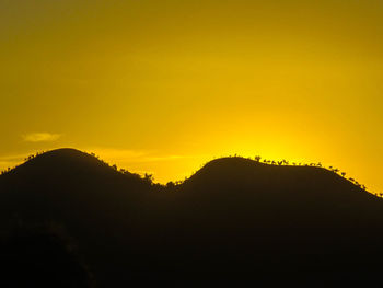 Scenic view of silhouette mountains against orange sky