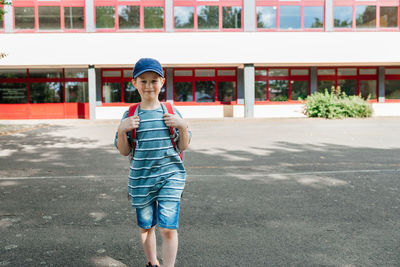 A charming european boy with a backpack on his back and a cap walks from school.