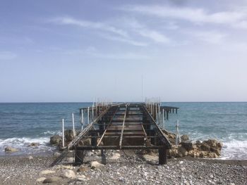 Pier on beach against sky