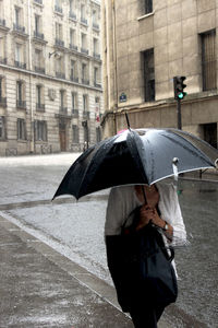 Woman with umbrella standing on street during rainy season