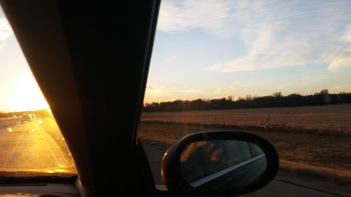 Close-up of side-view mirror against sky