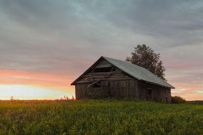 House on field against sky during sunset