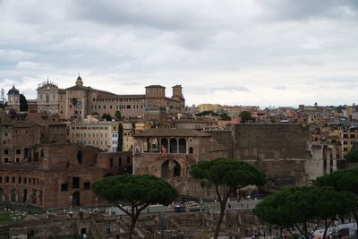 Buildings in town against cloudy sky