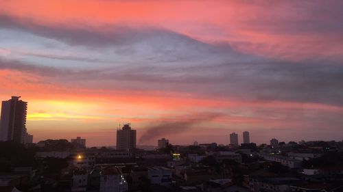 Buildings in city against romantic sky at sunset