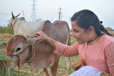 Woman touching calf on field