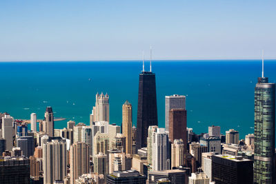 Modern buildings by sea against sky in city