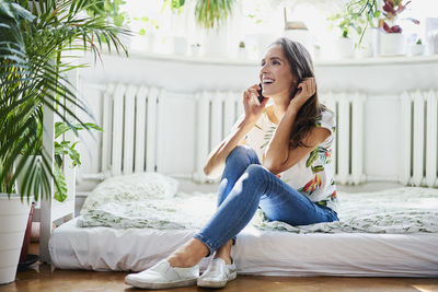 Happy young woman talking on the phone at home