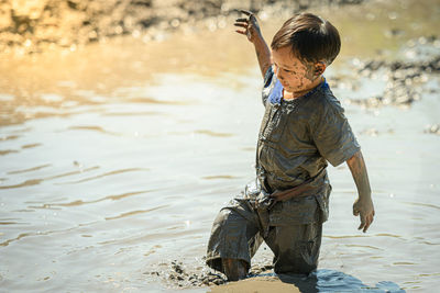 Smiling boy playing on mud outdoors