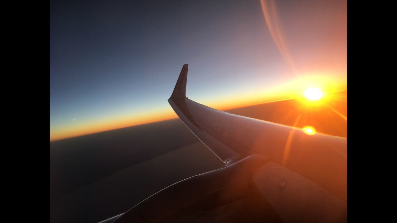 AIRPLANE WING AGAINST SKY AT SUNSET