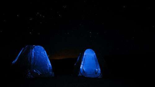 Rear view of people sitting against blue sky at night