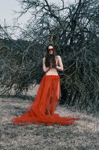 Portrait of shirtless young woman standing against plants