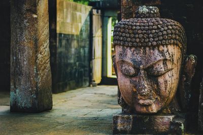 Close-up statue of buddha against old building