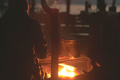 Rear view of a tourist sitting at fireplace by the shore