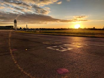 Airplane on runway against sky during sunset