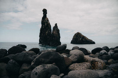 Rocks on sea shore against sky