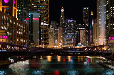 Illuminated bridge over river in city at night