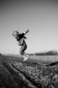 Man jumping on field against clear sky