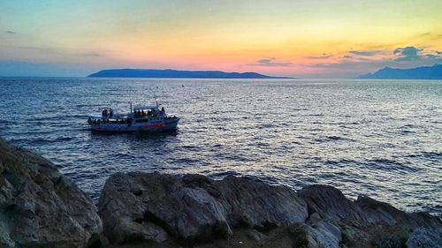 Boat sailing on sea against sky during sunset