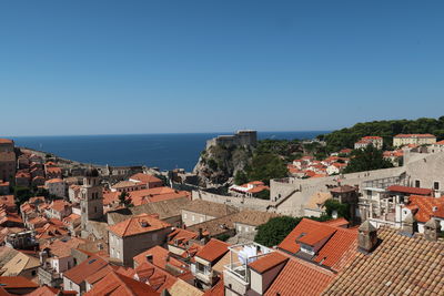 High angle view of townscape by sea against clear blue sky