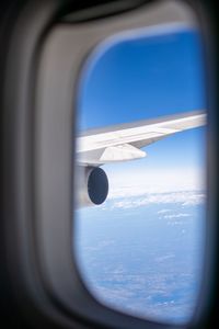 Airplane flying in sky seen through glass window