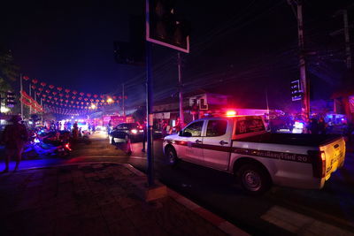 Cars on road by illuminated buildings in city at night