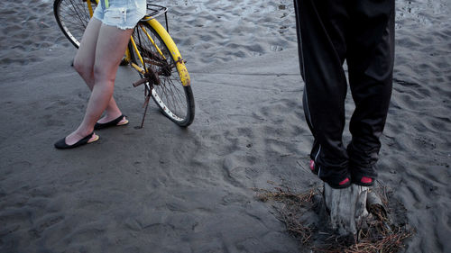 Low section of woman with bicycle on sand