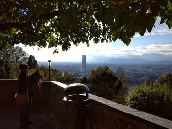 People standing by railing in city against sky