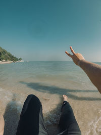 Low section of person in sea against sky