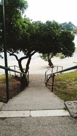 Empty footpath by park against sky