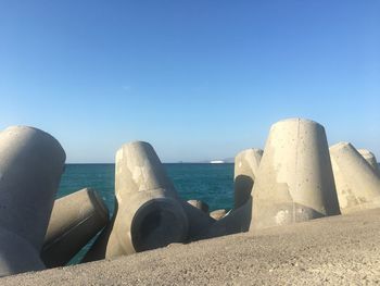 Tetrapods at beach against blue sky