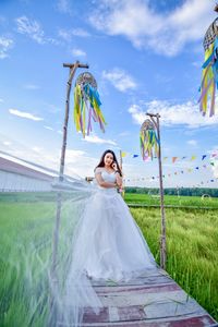 Young bride standing on field against sky