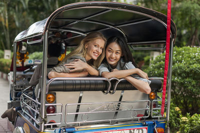 Smiling friends in rickshaw, thailand