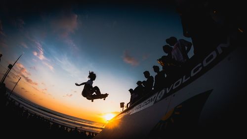 Low angle view of silhouette man jumping against sky during sunset