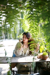 Portrait of young woman standing amidst plants