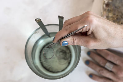 Cropped hand of woman tweezers in water