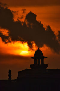 Silhouette building against dramatic sky during sunset