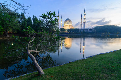 View of mosque by river against sky