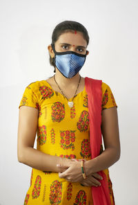 Portrait of woman wearing flu mask standing against white background
