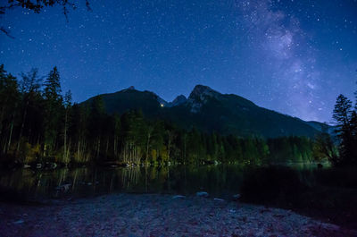 Scenic view of lake by mountains against sky at night