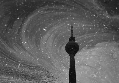 Water reflection of television tower in oil spilled puddle