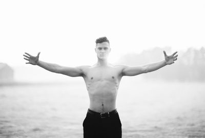 Full length of shirtless man standing against sky