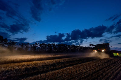 Illuminated machinery harvesting plants on field