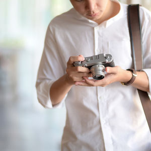 Midsection of man holding camera