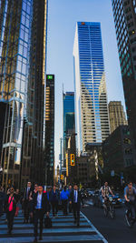 People on city street amidst buildings against sky