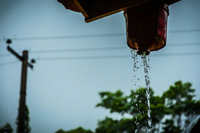 Low angle view of water falling from container against sky