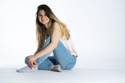 Portrait of smiling young woman sitting against white background