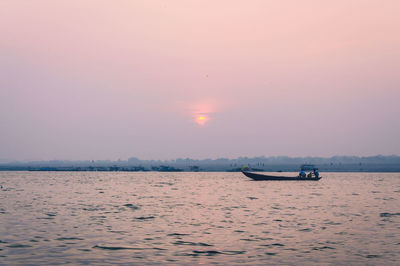 Boat sailing in sea at sunset